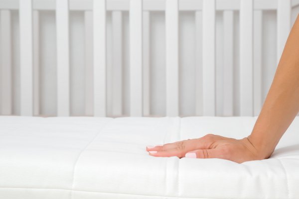Hand on baby crib mattress